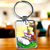 Porte-clé Diddl argenté rectangulaire avec illustration cartoon colorée de deux personnages sur un banc entourés de cœurs et vignes